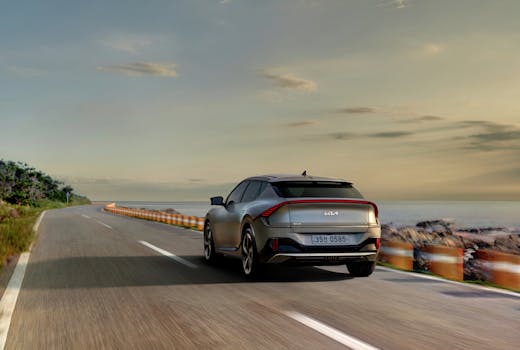 Explore the sleek Kia EV6 driving along a picturesque coastal road during sunset.