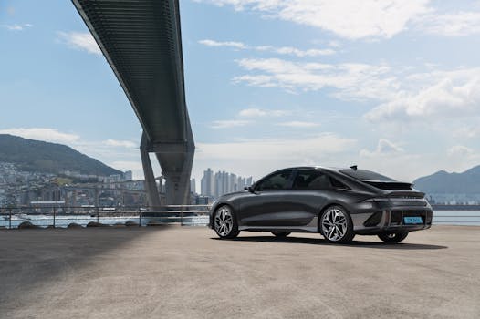 Sleek electric Hyundai car parked under a modern bridge in Busan, South Korea.