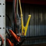 Close-up of colorful jumper cables hanging in a garage setting, showcasing selective focus.
