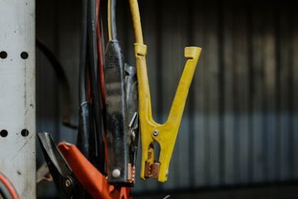 Close-up of colorful jumper cables hanging in a garage setting, showcasing selective focus.