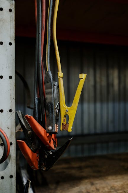 Close-up of colorful jumper cables hanging in a garage setting, showcasing selective focus.