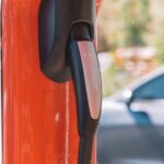 Close-up of an electric car charging station with blurred vehicle in the background.